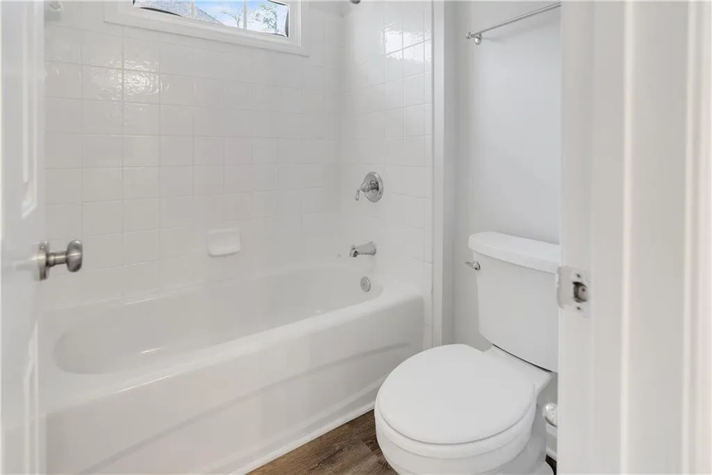Bathroom with toilet, tub / shower combination, and wood finished floors