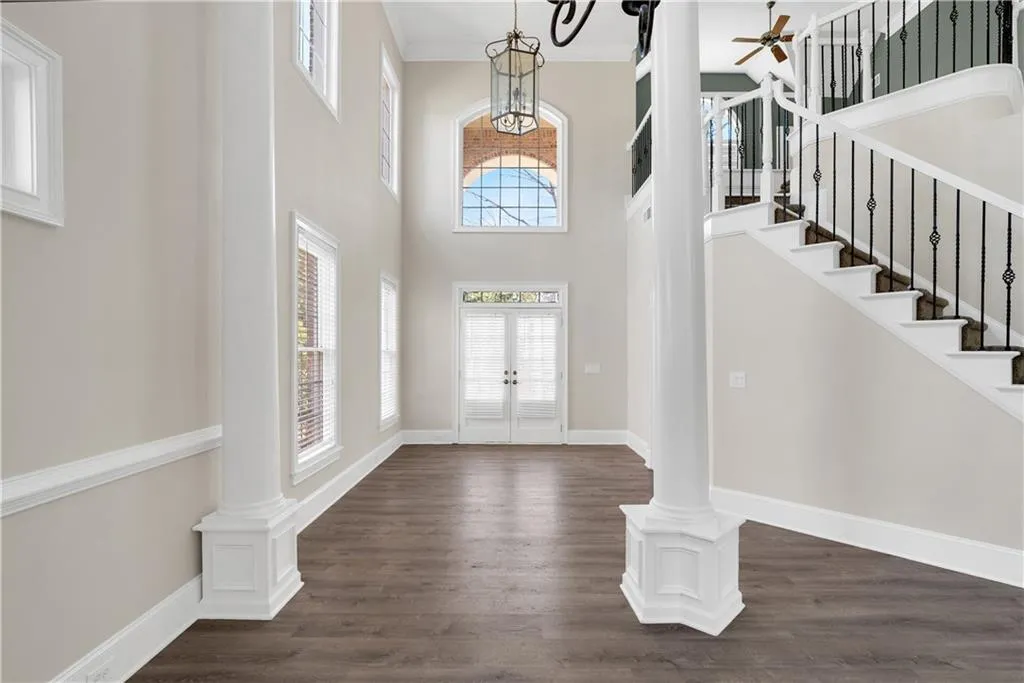 Entryway featuring ornate columns, stairs, baseboards, and dark wood-type flooring