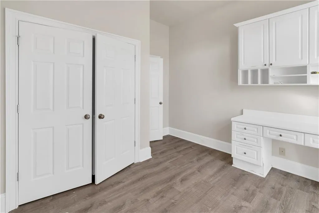 Unfurnished office with light wood-style floors, built in desk, and baseboards