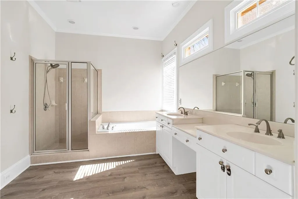 Bathroom with a bath, crown molding, and a sink