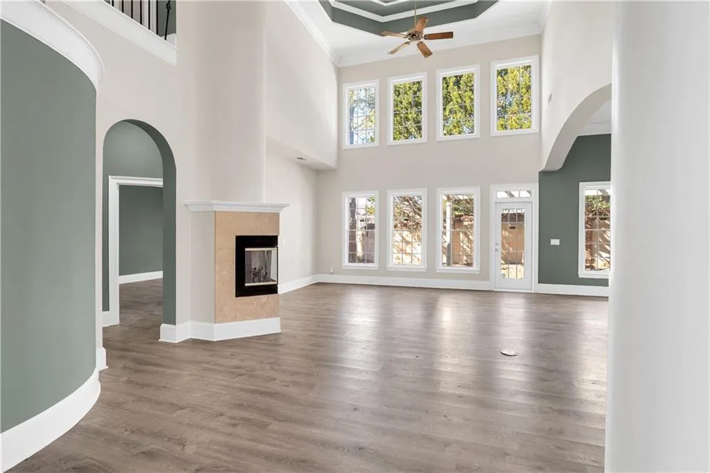 Unfurnished living room featuring crown molding, baseboards, wood finished floors, and a tile fireplace