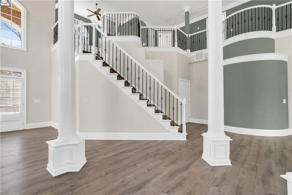 Foyer with decorative columns, baseboards, a ceiling fan, wood finished floors, and a high ceiling