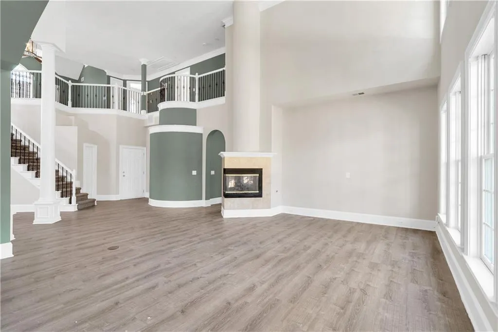 Unfurnished living room with a wealth of natural light, a tile fireplace, light wood-type flooring, and stairway