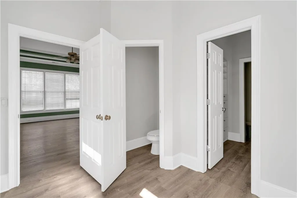 Bathroom featuring baseboards, toilet, ceiling fan, wood finished floors, and baseboard heating