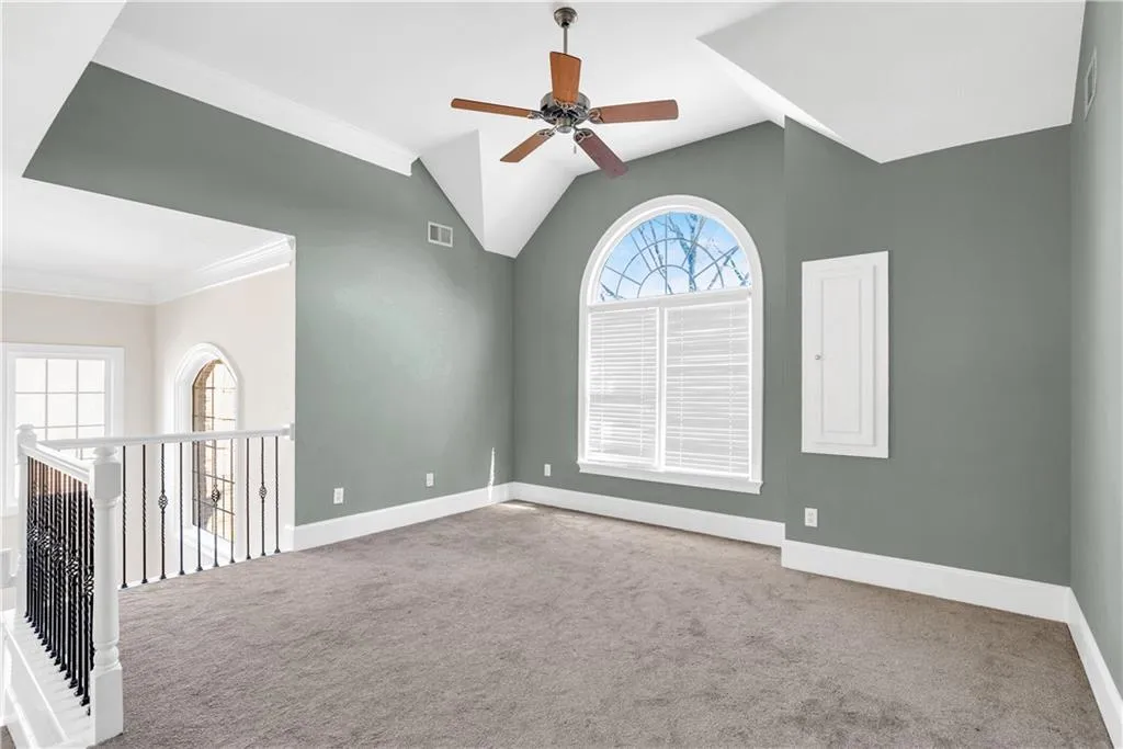 Unfurnished room with carpet, visible vents, vaulted ceiling, and baseboards