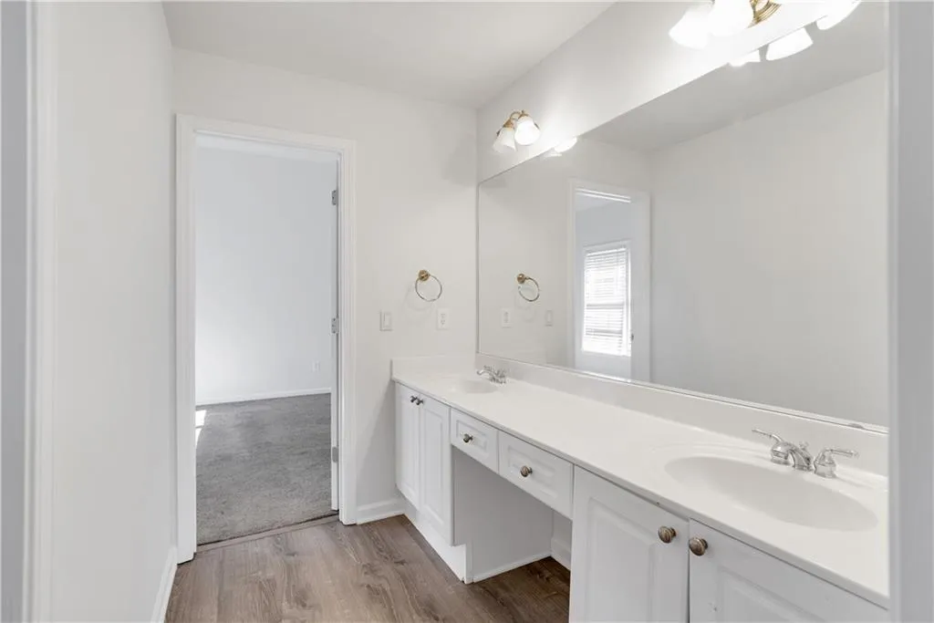 Bathroom featuring wood finished floors, a sink, baseboards, and double vanity