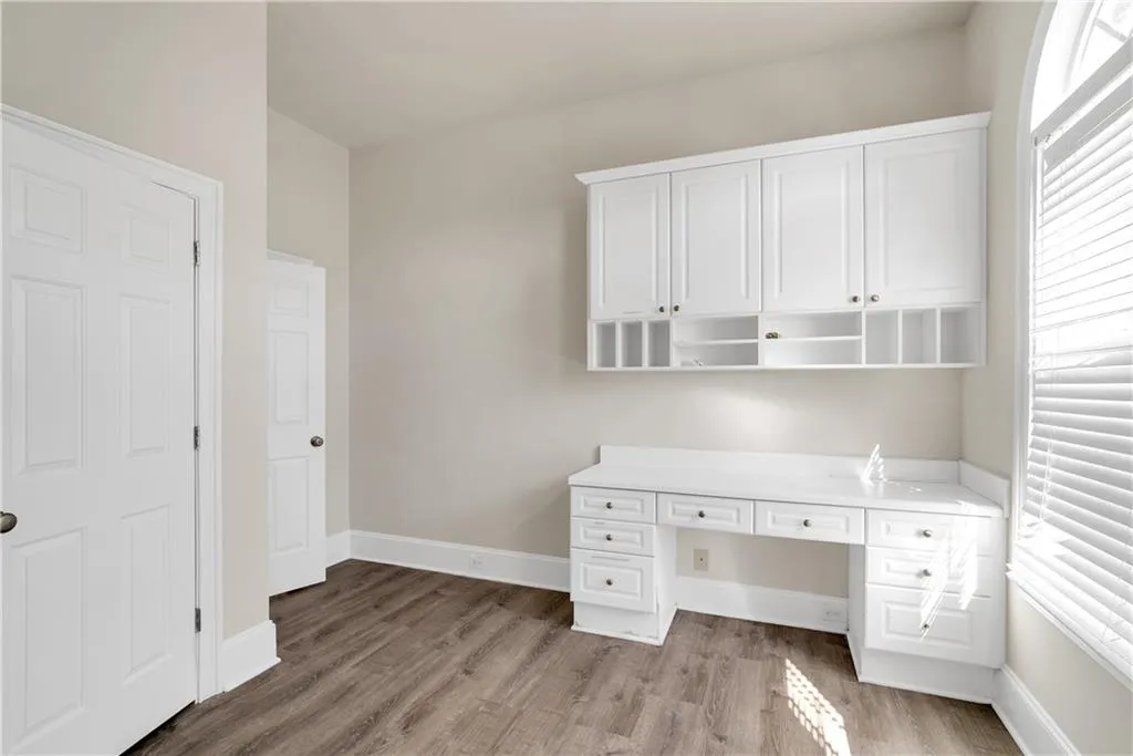 Unfurnished office featuring built in desk, light wood-style flooring, and baseboards