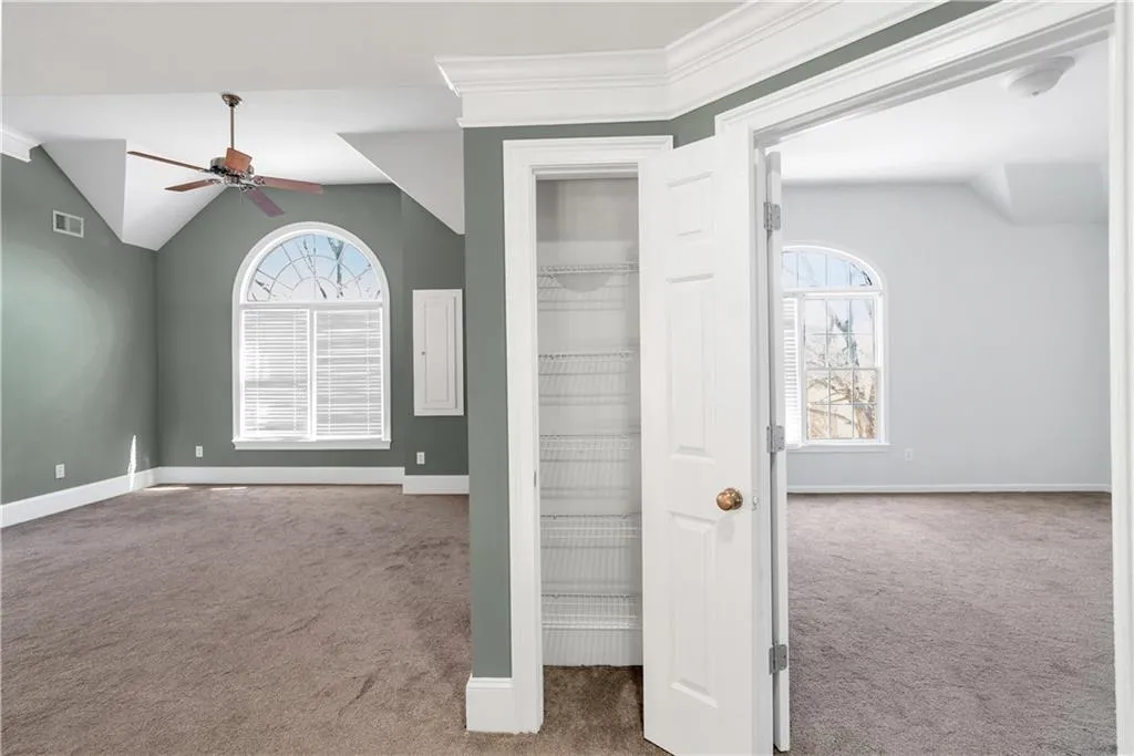 Unfurnished bedroom featuring carpet floors, lofted ceiling, visible vents, and baseboards
