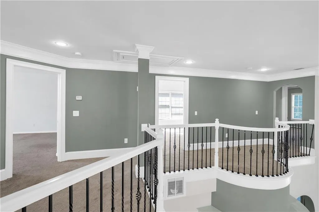 Hallway featuring an upstairs landing, baseboards, visible vents, carpet, and crown molding