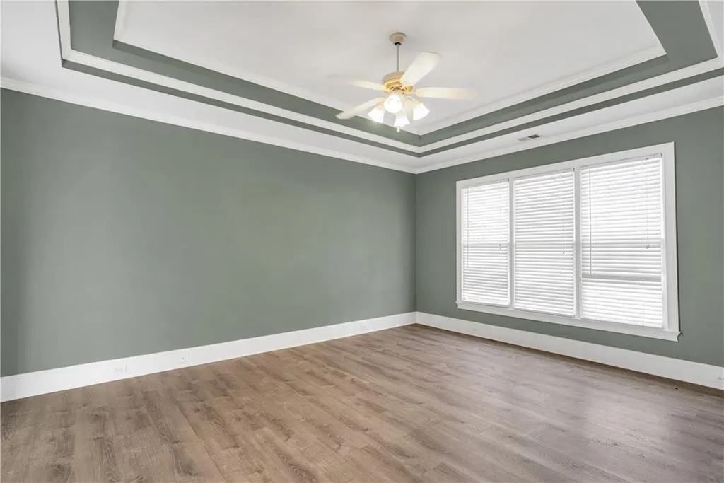 Unfurnished room with light wood finished floors, ornamental molding, and a raised ceiling