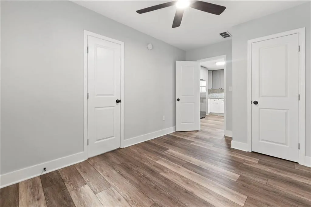 Unfurnished bedroom featuring light wood-type flooring, ceiling fan, and stainless steel fridge