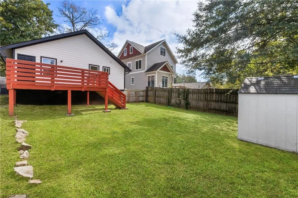 Rear view of house featuring a shed, a deck, stairway, and a fenced backyard
