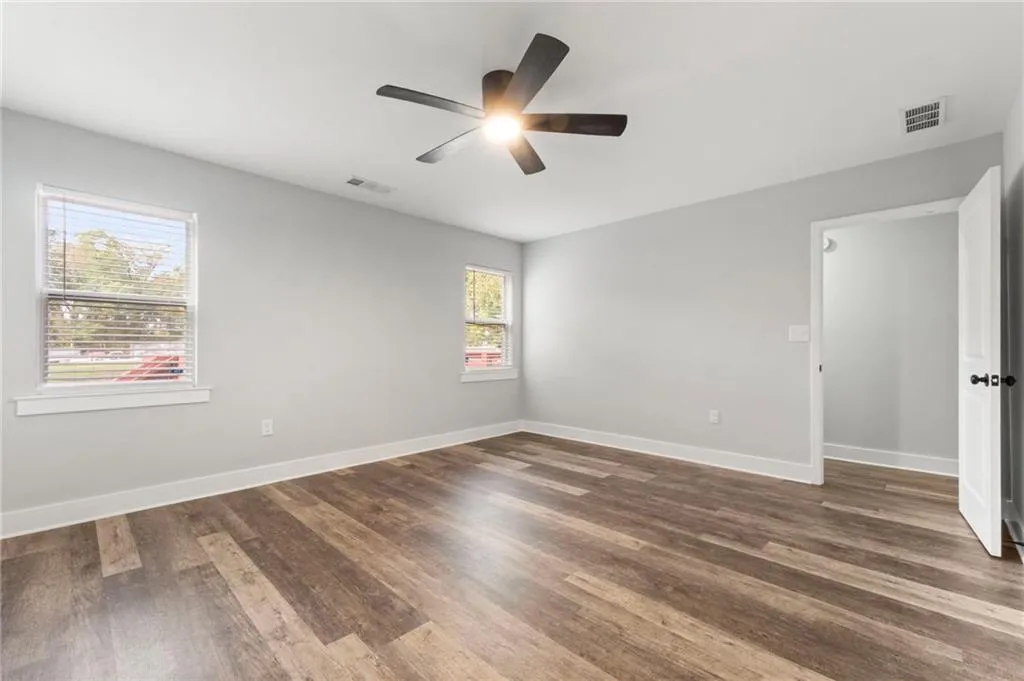 Empty room with dark wood-style floors and ceiling fan