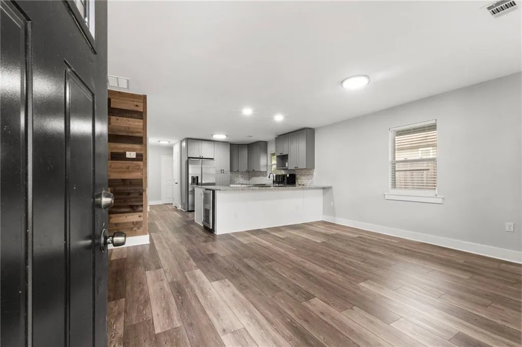Kitchen with gray cabinets, dark wood-style floors, tasteful backsplash, a peninsula, and stainless steel fridge with ice dispenser