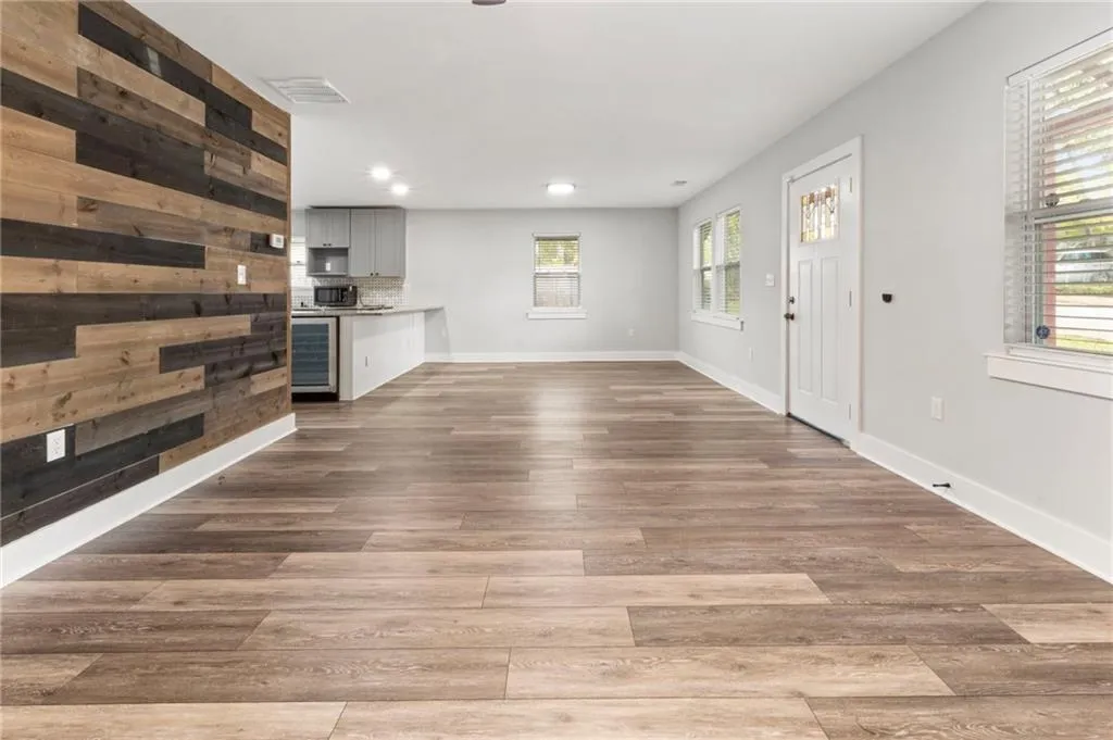 Unfurnished living room featuring wine cooler, wood finished floors, wood walls, and recessed lighting