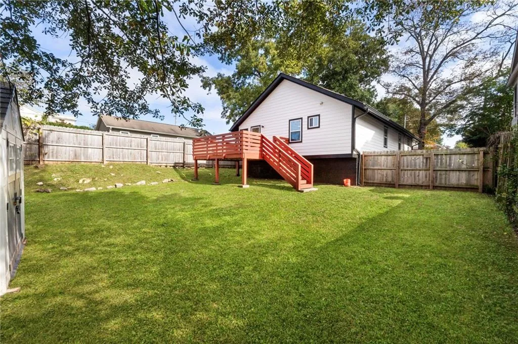 Rear view of house featuring stairs and a fenced backyard