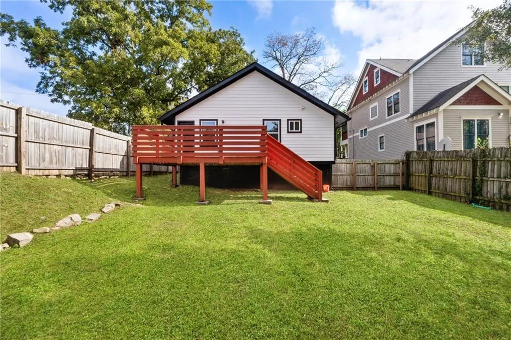 Rear view of property featuring a fenced backyard, stairs, and a deck