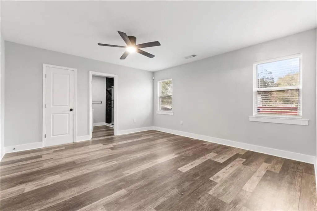 Unfurnished bedroom with a ceiling fan, light wood finished floors, and a walk in closet