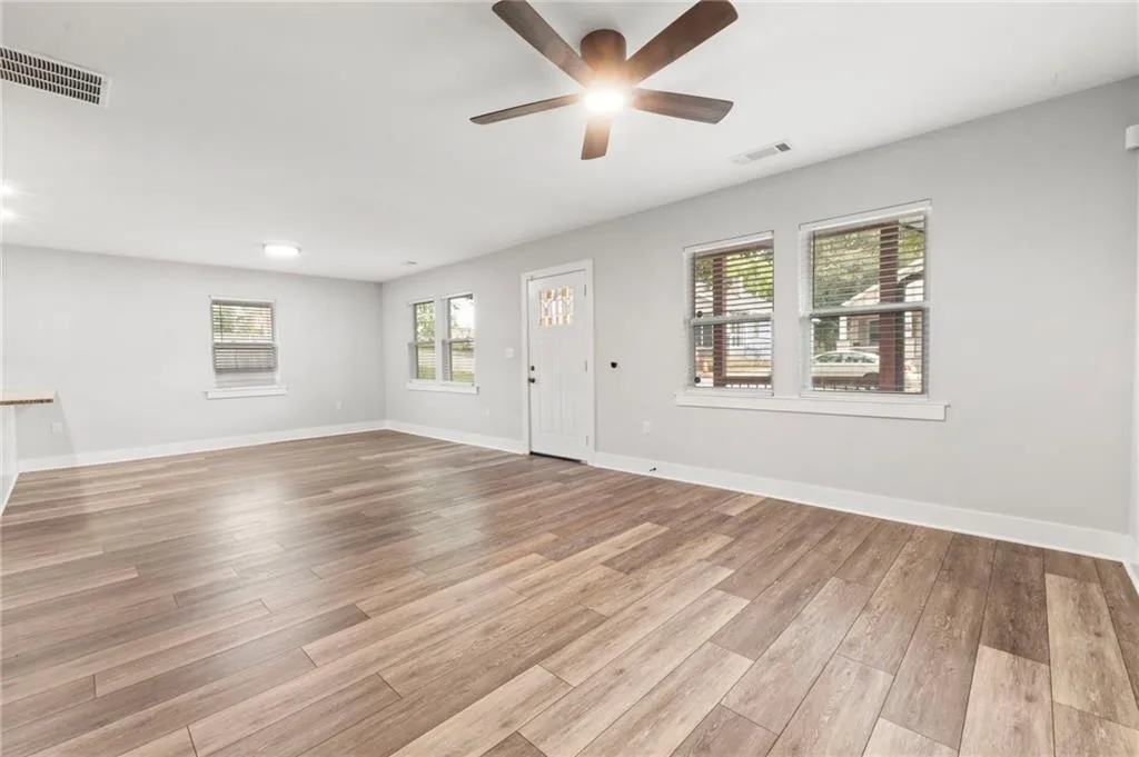 Unfurnished living room with healthy amount of natural light, light wood-style flooring, and a ceiling fan