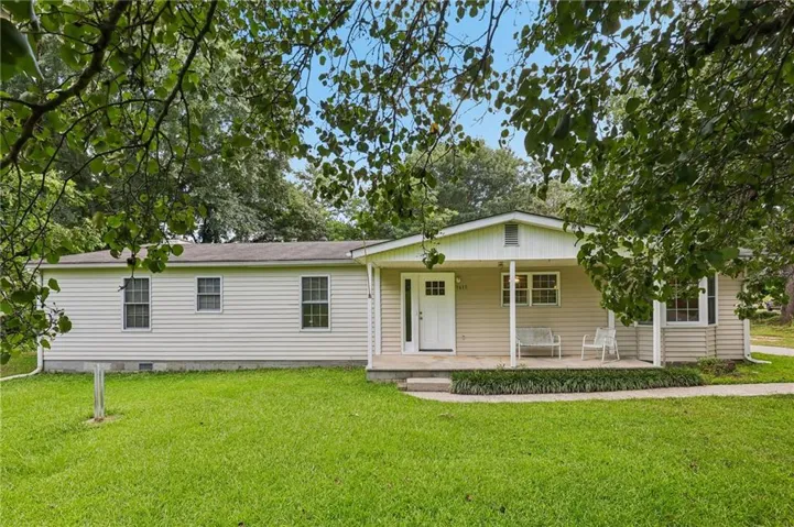 Single-story residence featuring light-colored siding, a covered front porch, a prominent front door with upper window panes, and multiple double-hung windows