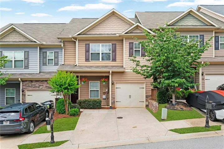 Two-story townhome with a single-car garage, concrete driveway, and covered entry