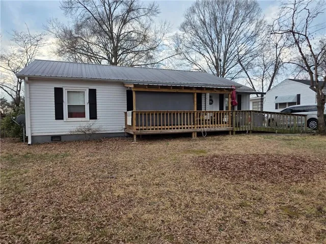 View of front of property with crawl space, a metal roof, and a wooden deck