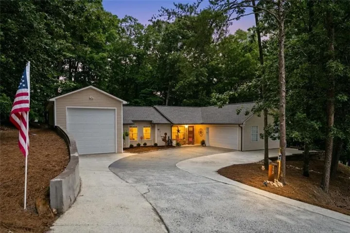 Ranch-style residence featuring a detached garage, an attached two-car garage, and a curved concrete driveway