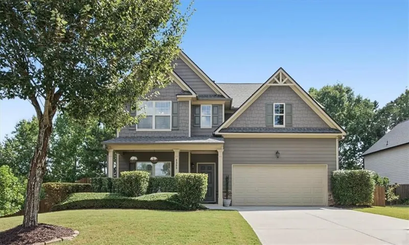 Two-story residence featuring a covered front porch, attached garage, and gabled rooflines with decorative accents