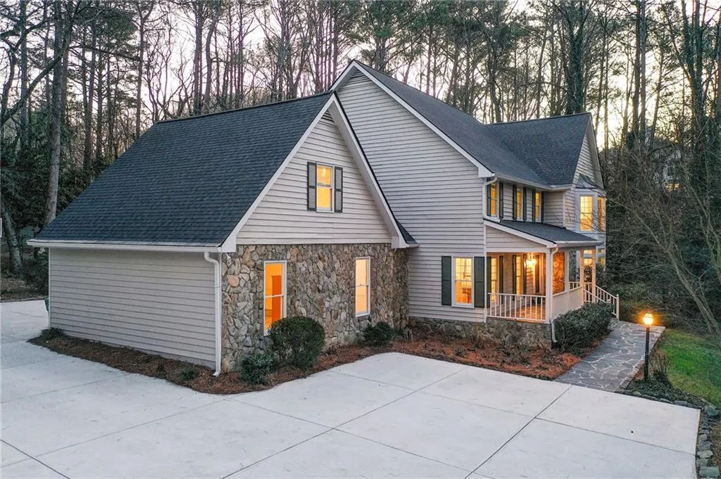 Traditional home featuring covered porch, stone siding, and roof with shingles