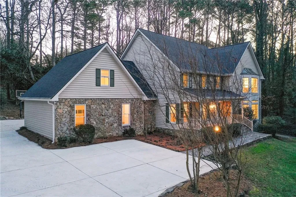 Traditional-style home featuring a shingled roof, stone siding, and a porch