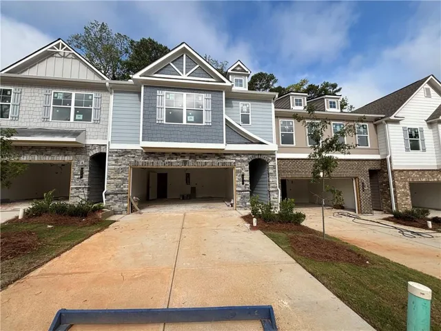 Multi-story townhomes with stone veneer accents, individual garage bays, and gabled roofs