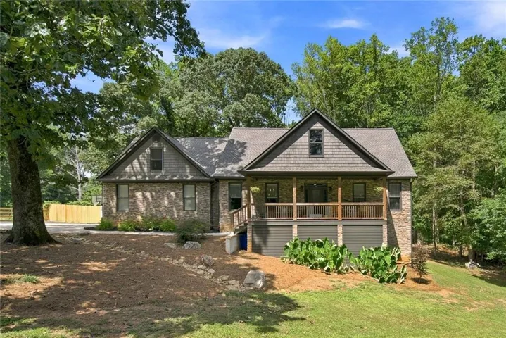 Stone and shake siding exterior with a covered porch, wood railing, and a gabled roofline
