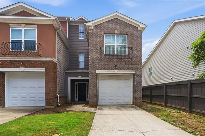 Brick-front townhome featuring a single-car garage and a second-story Juliet balcony with decorative iron railing