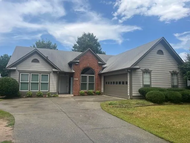 Red brick accents complement the siding exterior of this single-story residence, featuring a two-car garage and a curved driveway