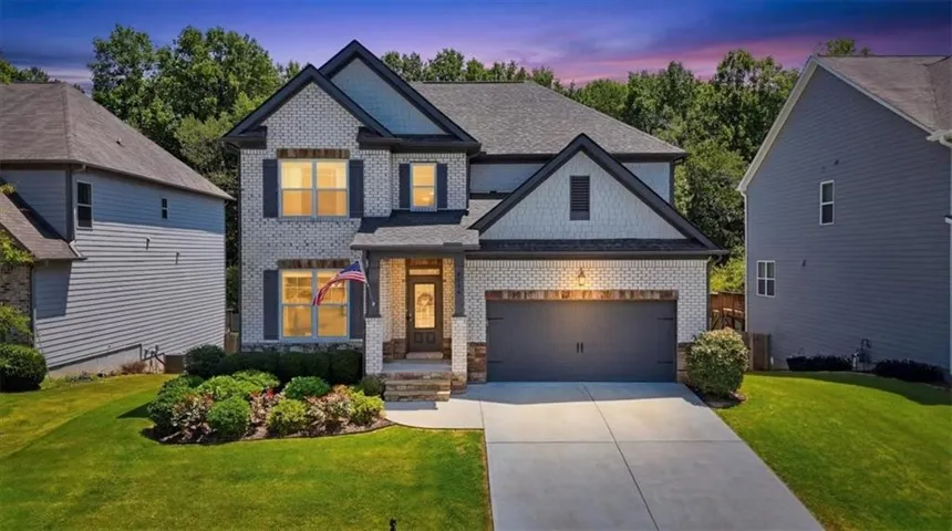 Two-story exterior with light brick and dark siding accents, covered front entry, attached two-car garage, and a concrete driveway