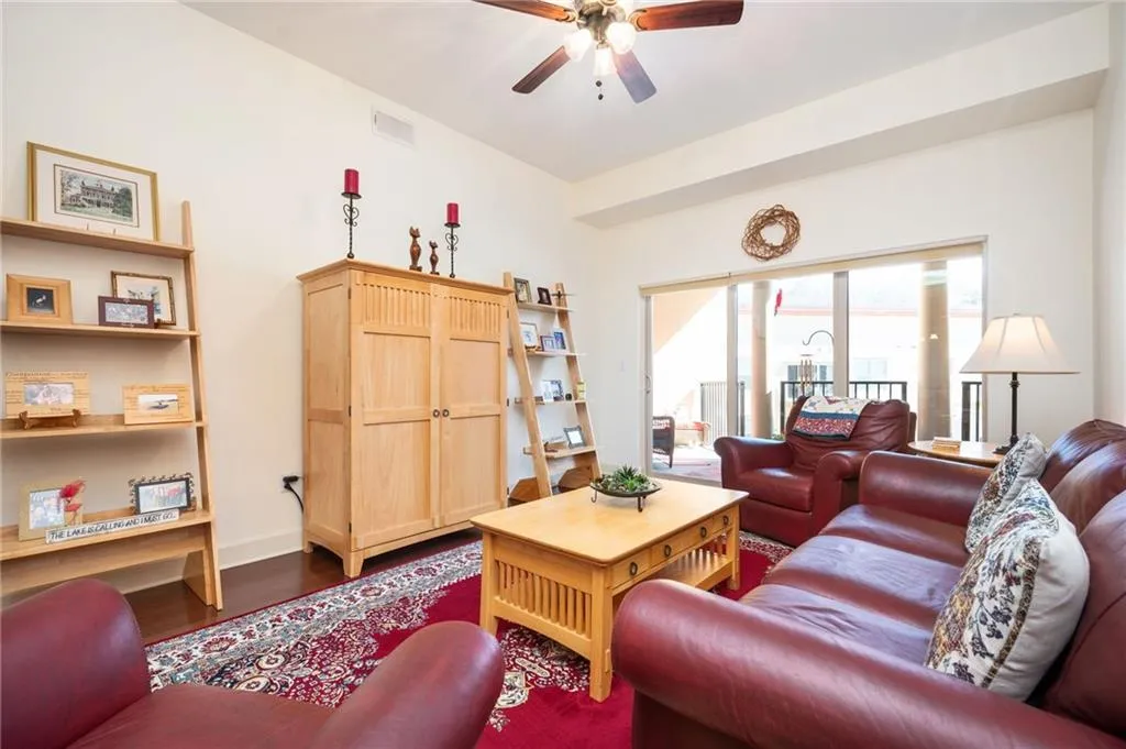 Living area with dark wood finished floors, visible vents, baseboards, and ceiling fan