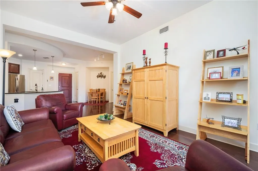 Living area with visible vents, a ceiling fan, dark wood-style floors, rail lighting, and baseboards