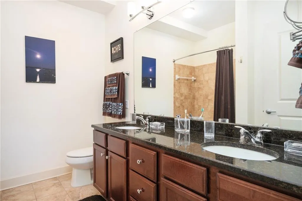 Bathroom featuring tile patterned floors, toilet, a shower with shower curtain, and a sink