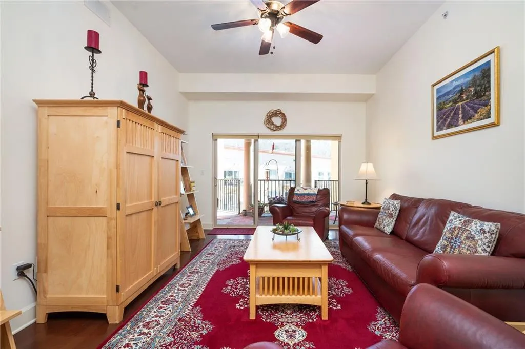 Living area with a ceiling fan, dark wood-style flooring, and baseboards