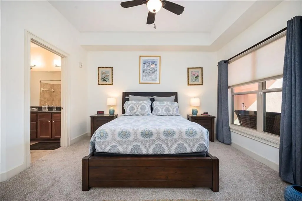 Bedroom with ensuite bathroom, a ceiling fan, baseboards, and carpet floors