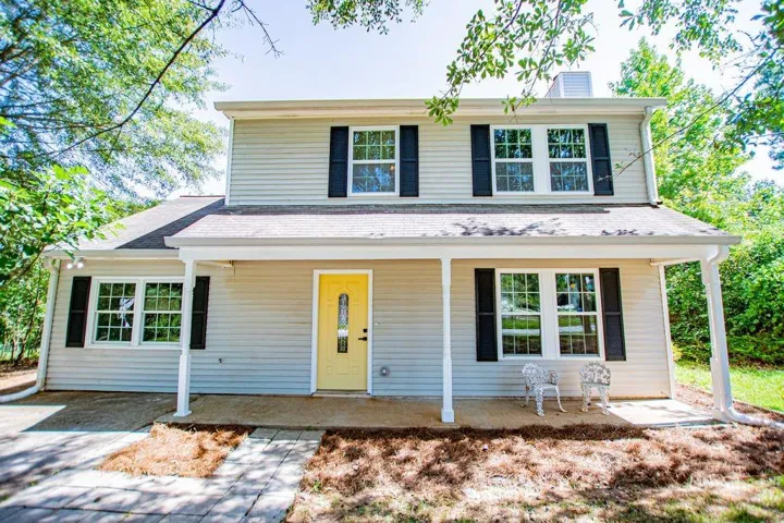 Two-story property featuring light-colored siding and a prominent yellow front door