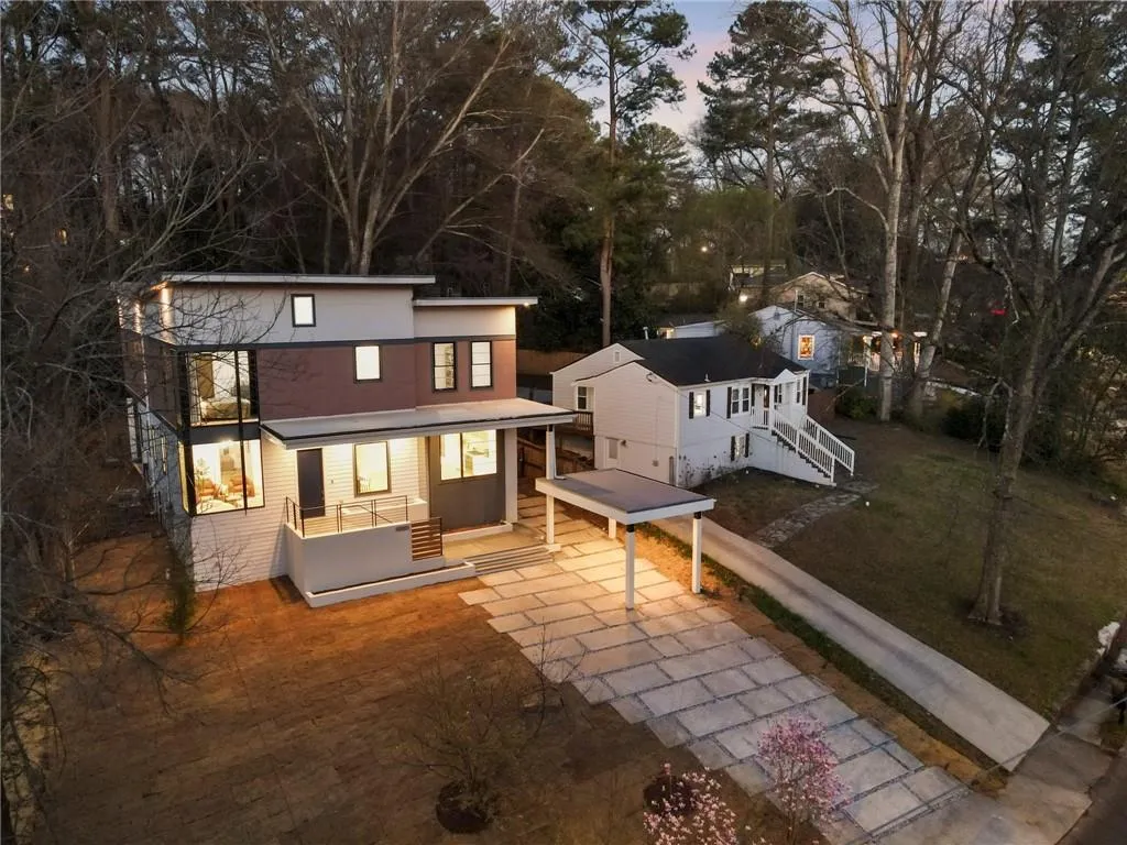 Front of house at dusk featuring concrete driveway, stairway, a lawn, and view of wooded area