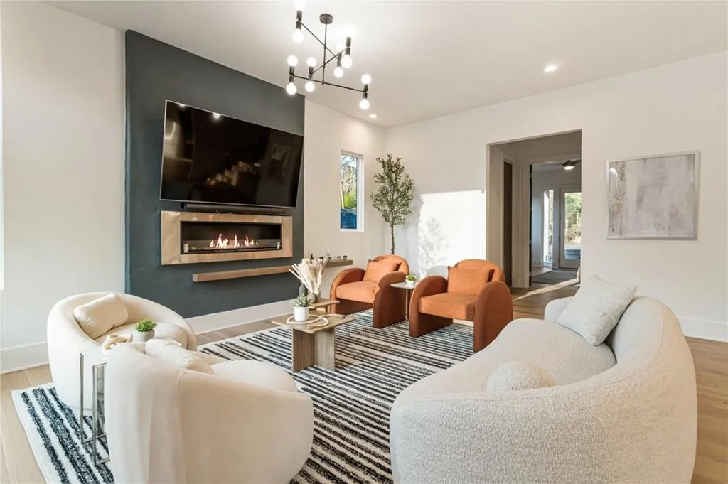 Living room with wood finished floors, a large fireplace, a chandelier, baseboards, and recessed lighting
