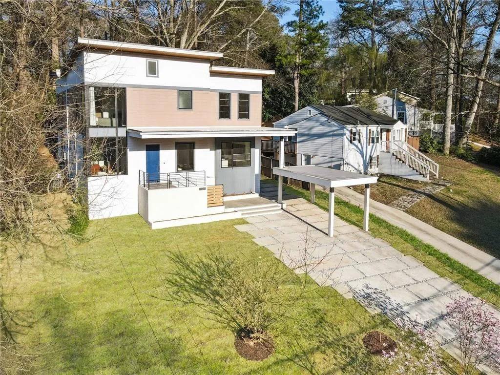 Front view of property with driveway, a lawn, view of wooded area