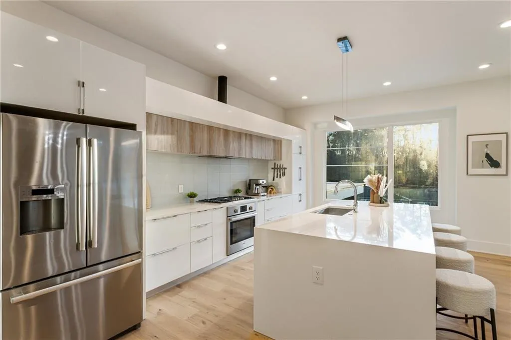 Kitchen featuring appliances with stainless steel finishes, modern cabinets, a sink, light wood-style flooring, and a kitchen bar