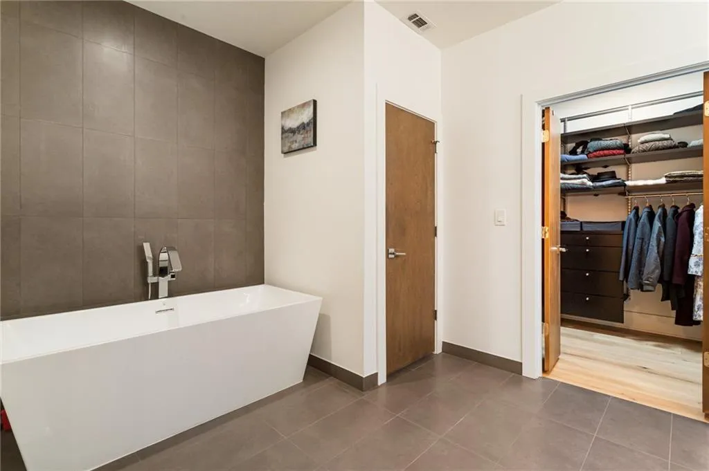 Bathroom featuring a freestanding tub, tile patterned flooring, a walk in closet, and baseboards