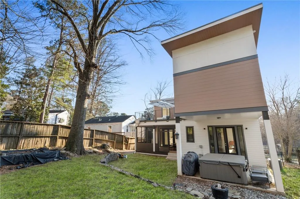Back of house with a hot tub and a balcony