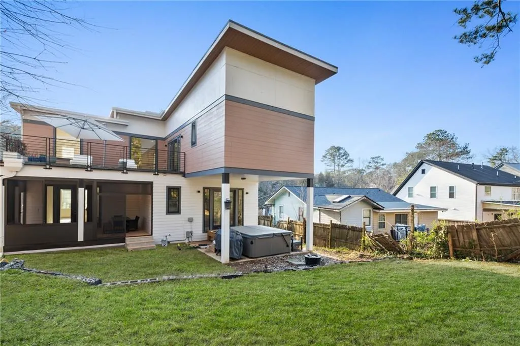 Rear view of property with a hot tub and a balcony