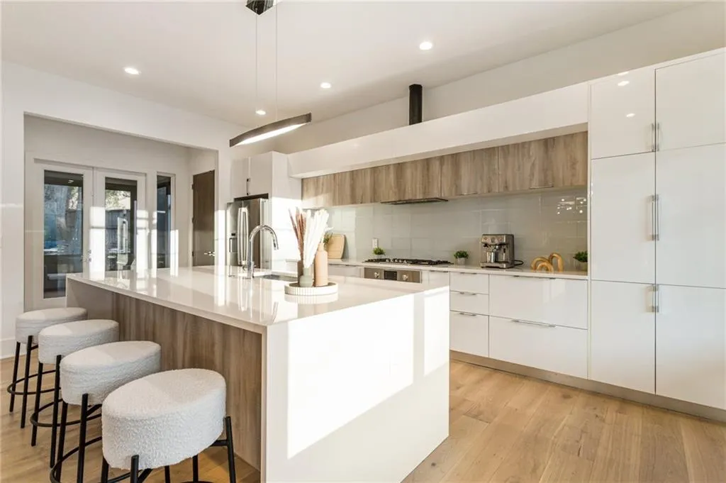 Kitchen featuring modern cabinets, appliances with stainless steel finishes, decorative backsplash, a breakfast bar, and recessed lighting