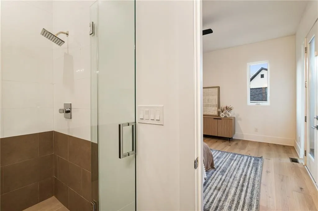Full bathroom featuring a shower stall, wood finished floors, baseboards, and radiator heating unit